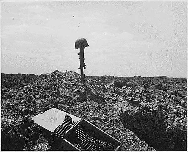 The beachhead is secure, but the price was high. A Coast Guard Combat Photographer came upon this monument to a dead American soldier somewhere on the shell-blasted shore of Normandy., ca. 06/1944. Credit: National Archives.