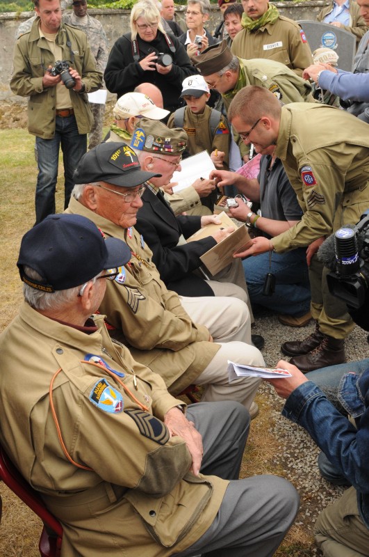 World War II veterans sign autographs after a commemoration ceremony at Angoville au Plain, France, June 4. The ceremony honors two medics from the 101st Airborne Division who rendered aid to 80 combatants and a local child in 1944 during the war. This ceremony is one of many in honor the 67th anniversary of the Normandy invasion. Credit: Staff Sgt. Tramel Garrett.