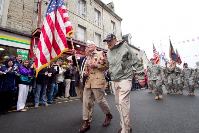 Zane Schlemmer, a veteran U.S. Army paratrooper who jumped into northern France as a sergeant with the 82nd Airborne Division, walks in his jump boots down the main street of Sainte Mere Eglise with other World War II veterans during the 67th anniversary of the Allied invasion of France, June 5, 2011. French citizens applaud as he and current paratroopers with the 82nd and other Army units parade past. Credit: U.S. Army photo by Sgt. Michael J. MacLeod