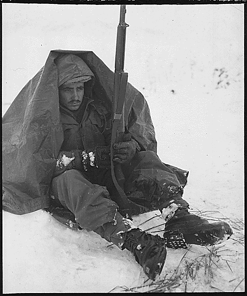 Private First Class Preston McKnight, 19th Infantry Regiment, uses his poncho to get protection from the biting wind and cold, in the Yoju area, Korea, during break in action against the Chinese Communist aggressors., 01/10/1951. Credit: National Archives