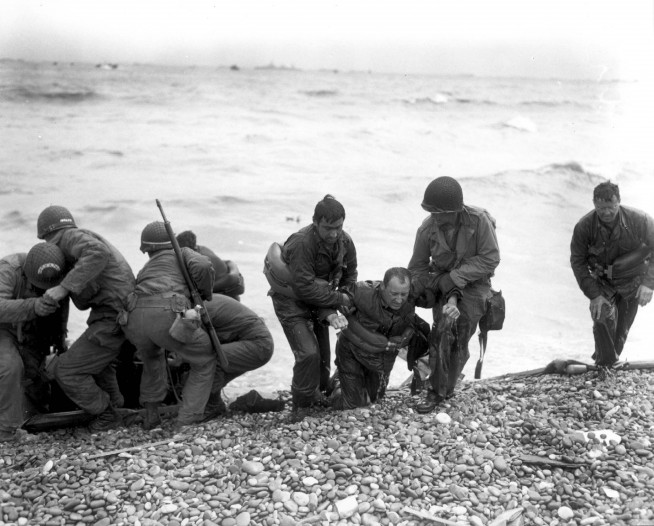 Members of an American landing party lend helping hands to other members of their organization whose landing craft was sunk by enemy action off the coast of France. These survivors reached Omaha Beach, by using a life raft. Image and caption credit: U.S. Army Center of Military History.