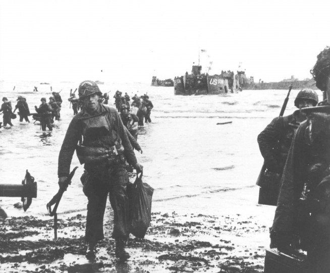 Invasion. Carrying a full equipment, American assault troops move onto Utah Beach on the norther coast of France. Landing craft, in the background, jams the harbor. 6 June 1944. Image and caption: U.S. Army Center of Military History.