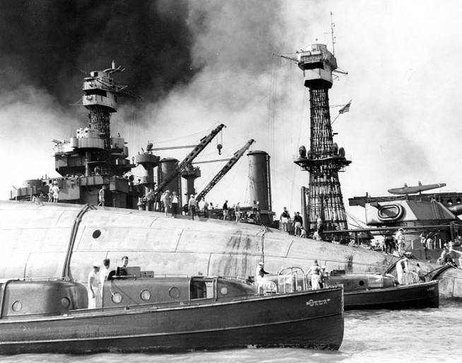 Rescue teams at work on the capsized hull of USS Oklahoma (BB-37), seeking crew members trapped inside, 7 December 1941. The starboard bilge keel is visible at the top of the upturned hull. Officers' Motor Boats from Oklahoma and USS Argonne (AG-31) are in the foreground. USS Maryland (BB-46) is in the background. Official U.S. Navy Photograph, National Archives Collection. Caption: Naval History & Heritage Command.