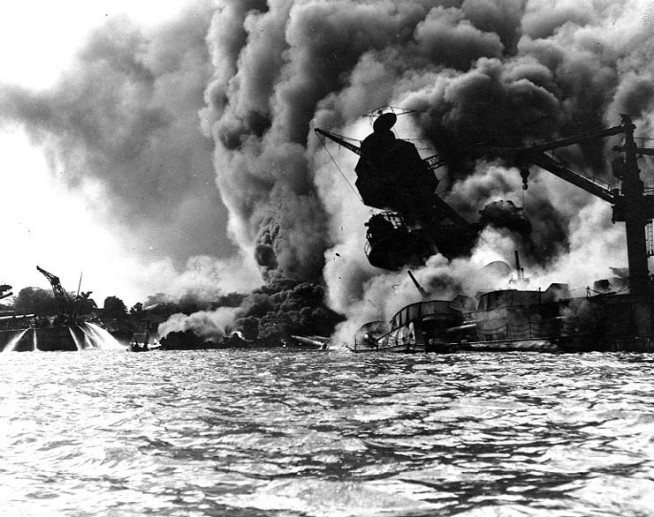 USS Arizona (BB-39) sunk and burning furiously, 7 December 1941. Her forward magazines had exploded when she was hit by a Japanese bomb. At left, men on the stern of USS Tennessee (BB-43) are playing fire hoses on the water to force burning oil away from their ship Official U.S. Navy Photograph, National Archives collection. Caption: Naval History & Heritage Command.