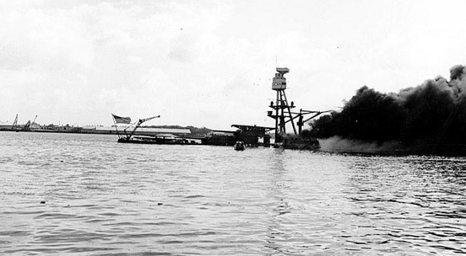 USS Arizona (BB-39) sunk and burning, with the National Ensign still flying at her stern. Official U.S. Navy Photograph, National Archives collection. Caption: Naval History & Heritage Command.