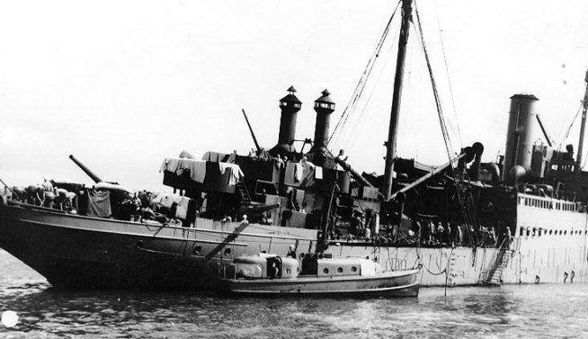 USS Vestal (AR-4) after she was beached in Pearl Harbor on 7 December 1941. She had been damaged by Japanese bomb hits during the raid. An Officers' Motor Boat is alongside her starboard quarter. Official U.S. Navy Photograph, NHHC Collection. Caption: Naval History & Heritage Command.
