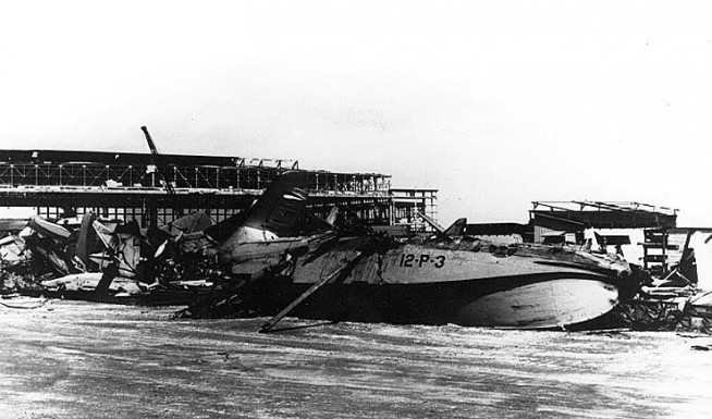 Aircraft wreckage and a badly damaged hangar at Naval Air Station, Kaneohe Bay, Oahu, shortly after the Japanese air attack. Plane in the foreground is a PBY of Patrol Squadron 12, marked "12-P-3". Photo and Caption: Naval History & Heritage Command.