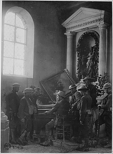 Squad of American soldiers listening to one of their comrades playing the organ in the half-wrecked old church in Exermont, in the Argonne. France, October 11, 1918. Credit: National Archives.