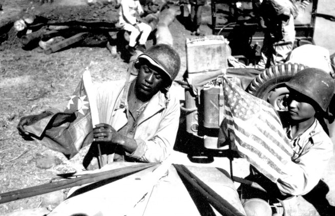A U.S. Army soldier and a Chinese soldier place the flag of their ally on the front of their jeep just before the first truck convoy in almost three years crossed the China border en route from Ledo, India, to Kunming, China, over the Stilwell road." February 6, 1945. Sgt. John Gutman. Image and caption credit: National Archives.