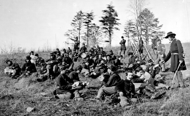 Soldiers at rest after drill, Petersburg, Va., 1864. The soldiers are seated reading letters and papers and playing cards. Image and caption credit: National Archives.