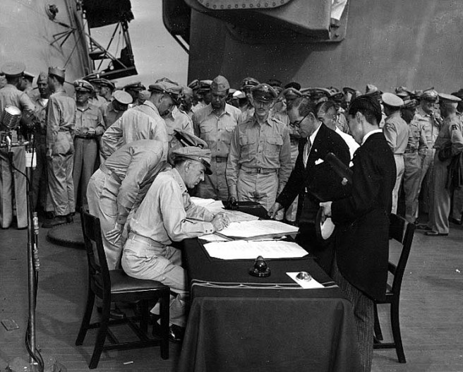 Lieutenant General Richard K. Sutherland, U.S. Army, Chief of Staff to General of the Army Douglas MacArthur, makes corrections to the Japanese copy of the Instrument of Surrender, at the conclusion of surrender ceremonies on board USS Missouri (BB-63), 2 September 1945. Japanese Foreign Ministry representatives Katsuo Okazaki (wearing glasses) and Toshikazu Kase are watching from across the table. Credit: Naval Historical Center.