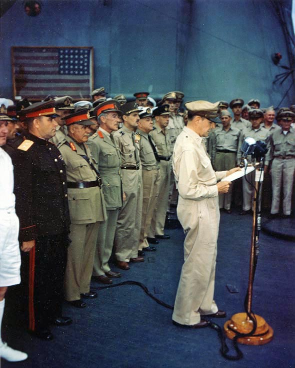 General of the Army Douglas MacArthur, Supreme Allied Commander, reading his speech to open the surrender ceremonies, on board USS Missouri (BB-63). The representatives of the Allied Powers are behind him, including (from left to right): Admiral Sir Bruce Fraser, RN, United Kingdom; Lieutenant General Kuzma Derevyanko, Soviet Union; General Sir Thomas Blamey, Australia; Colonel Lawrence Moore Cosgrave, Canada; General Jacques LeClerc, France; Admiral Conrad E.L. Helfrich, The Netherlands and Air Vice Marshall Leonard M. Isitt, New Zealand. Lieutenant General Richard K. Sutherland, U.S. Army, is just to the right of Air Vice Marshall Isitt. Off camera, to left, are the representative of China, General Hsu Yung-chang, and the U.S. representative, Fleet Admiral Chester W. Nimitz, USN. Framed flag in upper left is that flown by Commodore Matthew C. Perry's flagship when she entered Tokyo Bay in 1853. Credit: Naval Historical Center.
