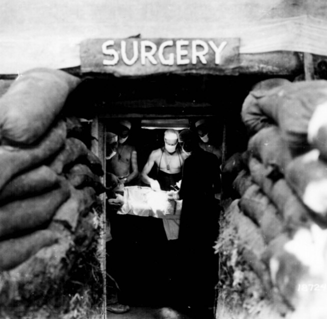 "In an underground surgery room, behind the front lines on Bougainville, an American Army doctor operates on a U.S. soldier wounded by a Japanese sniper." December 13, 1943. Image and caption credit: National Archives.